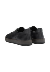 Sneakers negre din piele cu un finisaj neted, vârf rotunjit și profil jos. Toc texturat și talpă din cauciuc cu detalii de broderie contrastante.