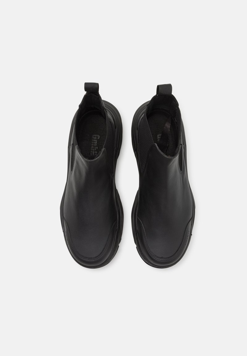 Zwarte instappers van glad leer, met elastische zijpanelen en een afgeronde teenvorm met een gestructureerde binnenzool.