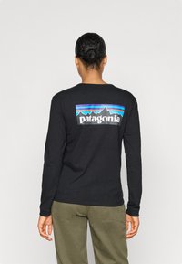 Fekete, hosszú ujjú póló színes hegy grafikával és "patagonia" felirattal a hátán. Pamutból készült, laza fazonú.