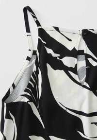 Schwarz-weiße ärmellose Bluse mit floralem Muster, V-Ausschnitt und Knopfverschluss auf der Rückseite, aus leichtem Stoff gefertigt.