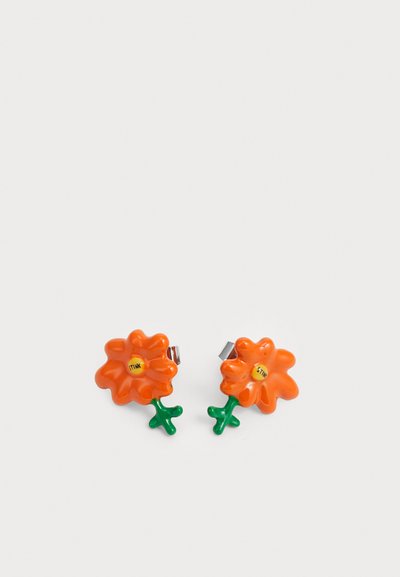 Orange blomsterformede øreringe med grønne stilke, lavet af glat plast. Hver ørering har en gul midte med ordet "STINK." De er med clips.
