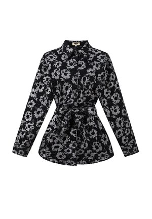 Chemise noire avec motif floral argenté, manches longues, col chemise et taille nouée pour marquer la silhouette. Tissu texturé avec fermeture à boutons.