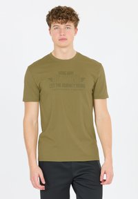 Oliivivihreä puuvillapaita lyhyillä hihoilla, jossa on mustalla kirjoitettu teksti, pyöreä pääntie ja rento fit. Yksinkertainen muotoilu.