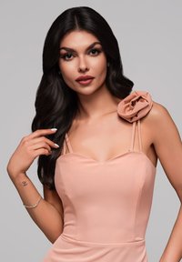 Robe ajustée rose clair avec un décolleté en cœur, des fines bretelles et une accent floral sur l'épaule. Tissu lisse avec une silhouette structurée.