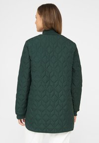 Grüne Steppjacke mit Stehkragen, gerippten Bündchen und einem Rautenmuster auf dem Stoff. Entworfen für eine lockere Passform.