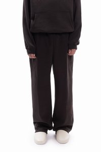 Sötétbarna kapucnis pulóver elülső zsebbel, hozzáillő bő szárú melegítőnadrággal, finom virágmintával a nadrágszárakon, fehér cipővel párosítva.