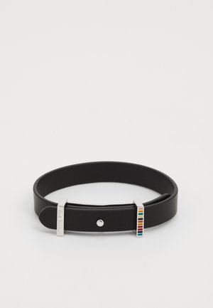 Bracelet en cuir noir avec boucle en argent et détail rayé multicolore à une extrémité sur fond blanc.