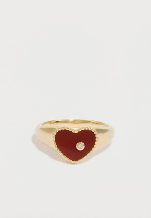 Gouden ring met hartvormige rood geëmailleerde middencentrale steen en een kleine doorzichtige steen, voorzien van een textuurrijke rand die op een touw lijkt.