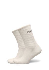 Chaussettes montantes en mélange de coton couleur beige clair, avec texture côtelée et logo décoratif imprimé sur le revers.