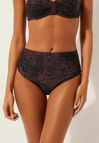 Leopardmuster-Bikini-Set mit einem gedrehten Bandeau-Oberteil und einem hochtaillierten Unterteil. Der Stoff ist dehnbar und hat eine glatte Textur in erdigen Tönen.