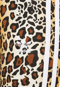 Sweatshirt i leopardmönster med svarta, bruna och beige nyanser. Inkluderar vita ränder och en broderad vit Adidas-logotyp.