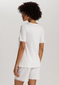 Conjunto de top de algodón blanco de manga corta y pantalones cortos. Presenta un dobladillo ondulado en las mangas y el bajo. Textura suave y corte relajado.