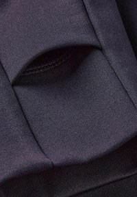 Dunkelblauer Stoff mit glatter Textur, der ein gefaltetes Taschendesign und sichtbare Nähte für zusätzlichen Details aufweist.