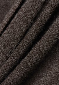 Detailní záběr tmavě hnědé pleteniny s viditelnými jemnými vlákny a složenou texturou.
