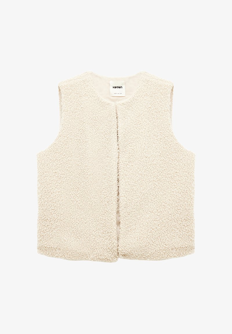 Kermavaiheessa oleva ilman hihoja oleva shearling-takki, jossa on pyöreä kaula-aukko ja auki oleva etuosa. Teksturoitu pehmeä fleece-kangas.