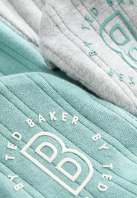 Dziane czapki w kolorze morskim i szarym, z prążkowaną fakturą. Logo w kolorze białym na morskim materiale. Gładkie wykończenie i swobodny design.