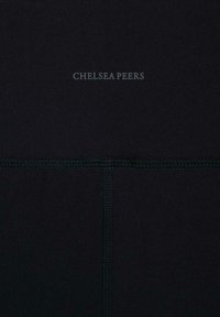 Černá tkanina s textem "CHELSEA PEERS" v šedé barvě. Hladká textura s jemnými detaily prošívání. Minimalistický design, žádné další viditelné vzory.