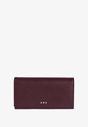 Portefeuille en cuir bordeaux avec une finition texturée, présentant trois clous dorés à l'avant, de forme rectangulaire et avec des bords cousus.