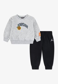 Γκρι φούτερ με το λογότυπο «JORDAN» και κίτρινη λεπτομέρεια, συνδυασμένο με μαύρο παντελόνι φλις με ελαστική μέση και λευκή λεπτομέρεια λογότυπου.