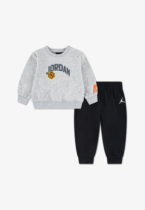 Felpa grigia con logo "JORDAN" e accento giallo, abbinata a pantaloni in pile neri con vita elastica e dettaglio logo bianco.