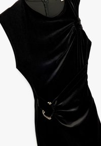 Czarna aksamitna sukienka bez rękaw�ów z zebranymi węzłami i złotymi pierścieniami na ramionach i w talii, z wysokim dekoltem i dopasowanym krojem.