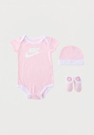 Różowy zestaw Nike dla niemowląt z body z krótkim rękawem, dopasowaną czapką i miękkimi bucikami, wszystkie z białym obszyciem i logo.