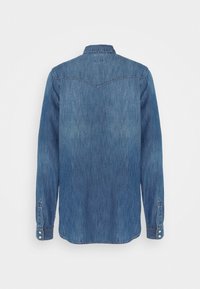 Vue de dos d'une chemise en denim bleu à manches longues avec col, poignets boutonnés et couture d'empiècement sur le haut du dos.