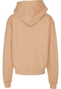 Hoodie van zacht perzikkleurig materiaal, met een relaxte pasvorm, geribbelde boorden en een ronde zoom. Glad textuur zonder zichtbare patronen.
