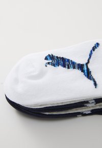 Baltos medvilnės kojinės su mėlynu ir juodu dryžuotu Puma logo. Sklandži tekstūra, su suapvalinta pirštine ir tamsiai mėlynu akcentu ant krašto.