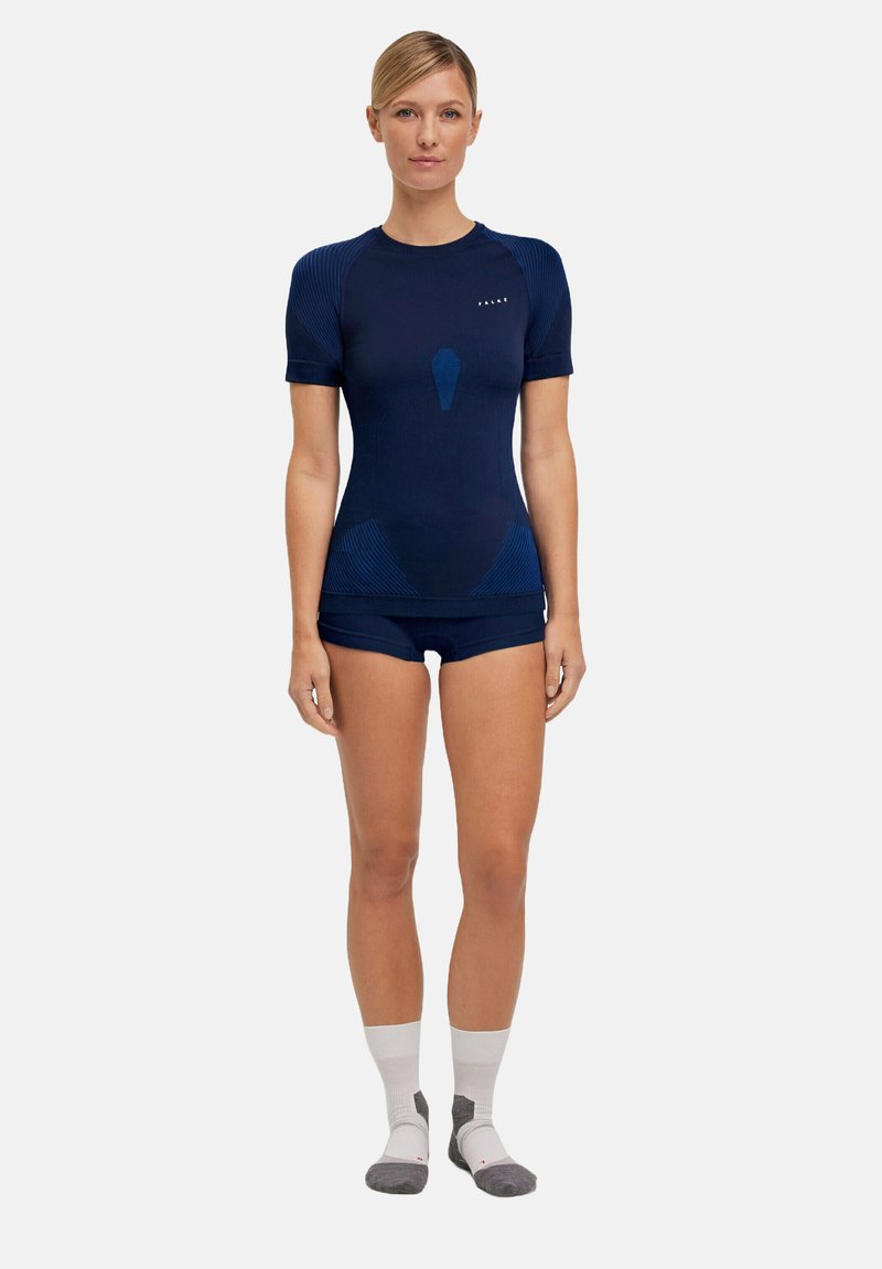 Granatowy sportowy top z krótkim rękawem, z tonowanymi prążkowymi akcentami, w zestawie z dopasowanymi szortami. Charakteryzuje się eleganckim, przylegającym krojem i rozciągliwym materiałem.