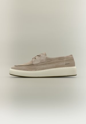 Beżowy casualowy but zamszowy na sznurowadła z białą grubą podeszwą, przeszyciami i subtelnym napisem marki po boku, pokazany w widoku z profilu.