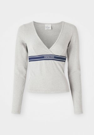 Tricou gri cu mânecă lungă, cu decolteu adânc în V și o panglică bleumarin pe piept, care prezintă textul "LETS FRANS". Fabricat dintr-un material moale și elastic.