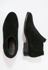 Black suede ankle boots with a low block heel, ribbed elastic side panels, smooth interior, and a sleek, minimal design.