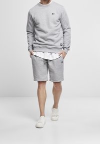 Sudadera gris y pantalones cortos a juego, confeccionados en una tela suave. Cuenta con un cuello redondo, banda elástica en la cintura y detalles del logotipo en ambas prendas.