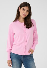 Ljusrosa cardigan med rund scallopkrage, framknäppning med knappar och delikata volanger längs kanterna och ärmsluten. Elastiskt tyg.