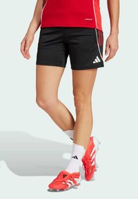 Black athletic shorts with red side accents, paired with bright red soccer cleats and white socks featuring black stripes.