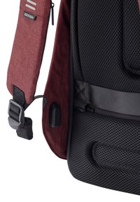 Cinghietto per spalla in tessuto rosso con imbottitura in rete, dettagli neri, fibbia regolabile e logo. Superficie testurizzata per una presa comoda e confortevole.