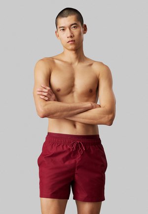 Pantaloni da bagno bordeaux con vita elastica e coulisse. Tessuto morbido, lunghezza sopra il ginocchio, design semplice, senza motivi visibili.