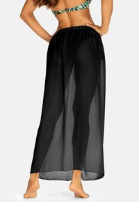 Czarny przezroczysty maxi okrycie z elastycznym pasem, lekkiego materiału i zwiewnym fasonie. Posiada prosty krój dla luźnego dopasowania.