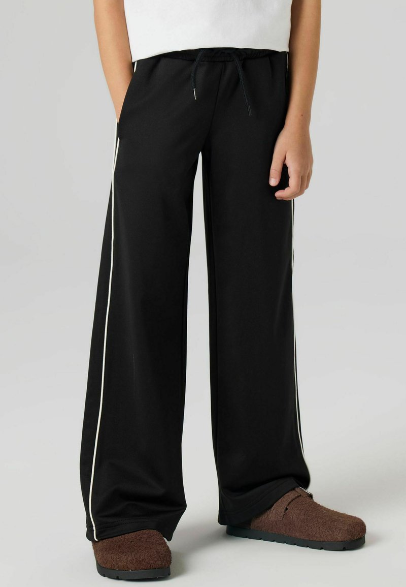 Svarte joggebukser med vide ben og snor i midjen, med hvite side-striper. Laget av mykt stoff, designet for komfort og enkelhet.