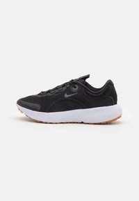 Zapatilla deportiva negra con parte superior de malla, suela de goma, un branding sutil y una entresuela blanca con detalles texturizados y suela de goma.
