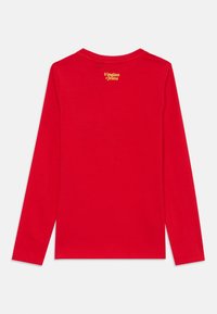 Camisetta a maniche lunghe rossa realizzata in tessuto morbido, con scollo rotondo e un piccolo logo di testo giallo posizionato sulla parte superiore della schiena. Design semplice.