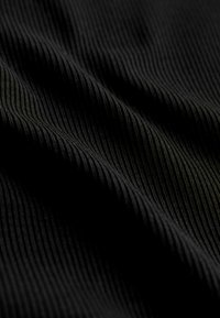 Schwarzer Stoff mit feiner gerippter Textur, die sanfte Wellen und einen subtilen Glanz zeigt. Das Material erscheint weich und flexibel.