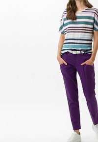 Stripet kortærmet top i teal, lilla og hvid; lilla tapered bukser; hvidt bælte og sneakers; afslappet pasform med lommer.