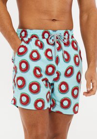 Costume da bagno con una base azzurro chiaro, caratterizzato da un motivo di angurie rosse e verdi. Vita elasticizzata con cordino e tasche laterali.