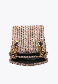 Piccola borsa a tracolla in tweed aperta con catene dorate e nere, che mostra un tessuto intrecciato testurizzato in beige, nero, rosso e fili metallici.