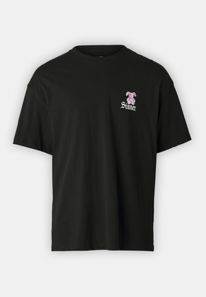 Czarna koszulka z krótkim rękawem z małym różowym misiem oraz białym napisem "Sinner" w lewym obszarze klatki piersiowej.