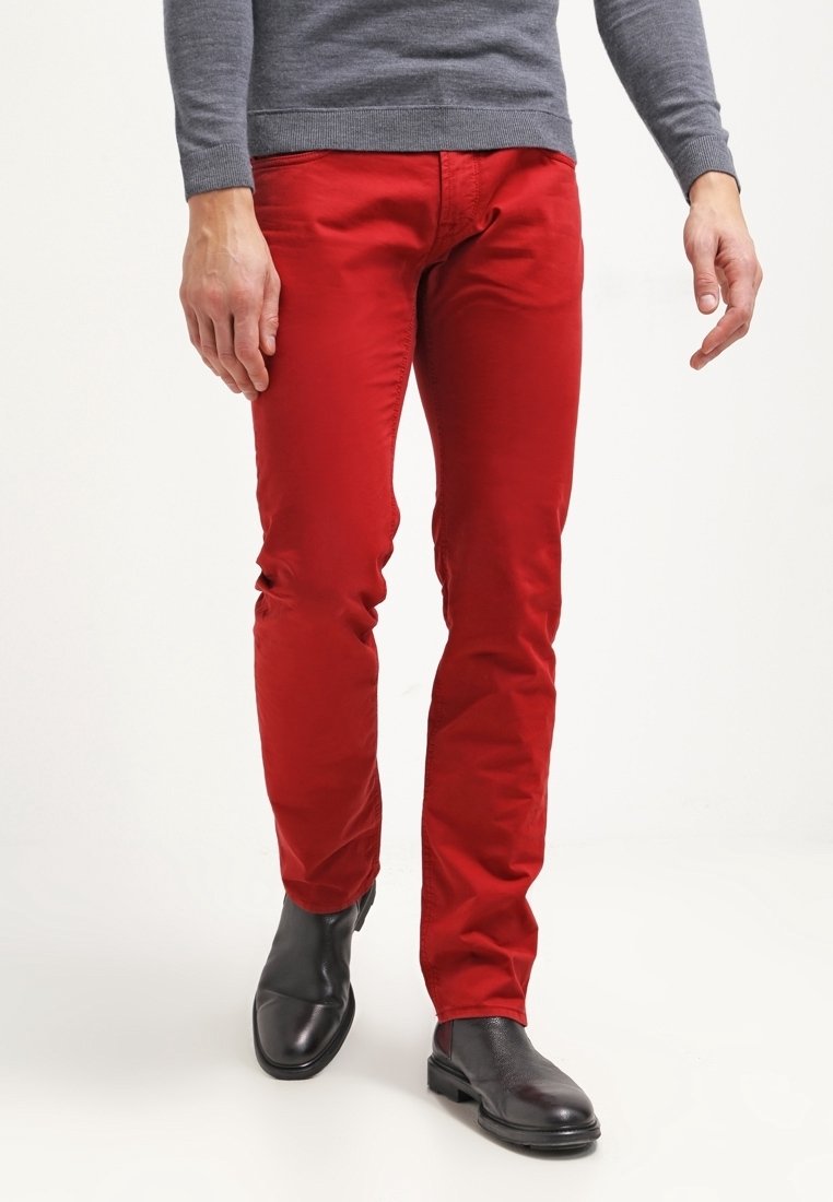 Pantaloni in cotone rosso con un design slim fit, cinque tasche e zip, abbinati a stivaletti neri.