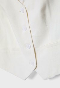 Valkoinen liivi, jossa neljä valkoista nappia ja kaksi halkiollista taskua, edessä kärkiosa helman alaosassa.