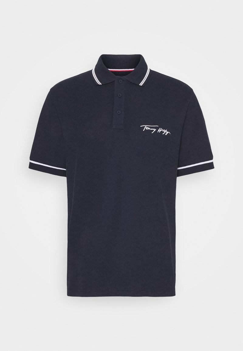 Polo bleu marine à manches courtes avec bordure blanche au col et aux manches, patte de boutonnage à trois boutons et logo Tommy Hilfiger blanc sur la poitrine.